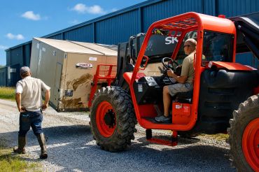 Forklift lifting a large appliance outdoors.
