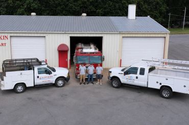 Group of workers in front of a fire station with trucks.