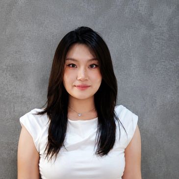 Portrait of a woman with long dark hair against a gray background.