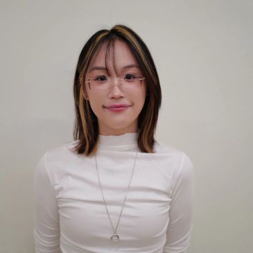 Young woman with glasses and highlighted hair smiles gently.
