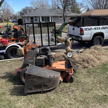 Lawn care equipment including a mower and trailer near a residential house.