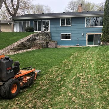A blue house with a lawn mower on freshly cut grass.