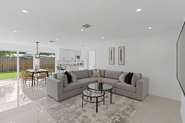 Bright modern living room with gray sectional sofa and glass coffee tables.