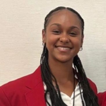 Smiling woman wearing a red blazer and braided hair.