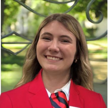 Young woman smiling in a red blazer.