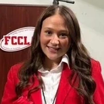 Young woman in a red blazer smiling at FCCLA event.