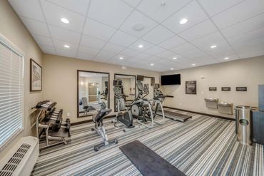 Modern gym with cardio equipment and weights in a clean room.