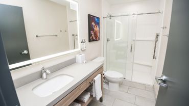 Modern bathroom with large mirror, vanity, and glass shower enclosure.