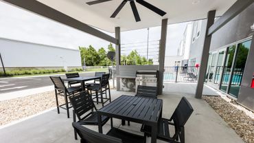 Modern outdoor seating area with black furniture and a ceiling fan.