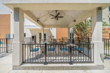 Outdoor covered patio with table and chairs under a ceiling fan.