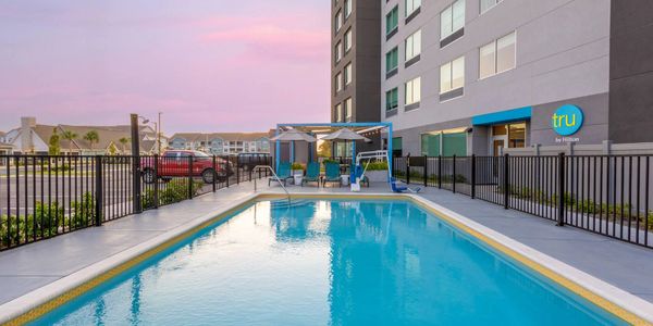 Outdoor swimming pool at a Tru by Hilton hotel during sunset.