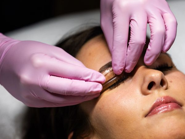 Applying eyebrow stencil on a woman's face.