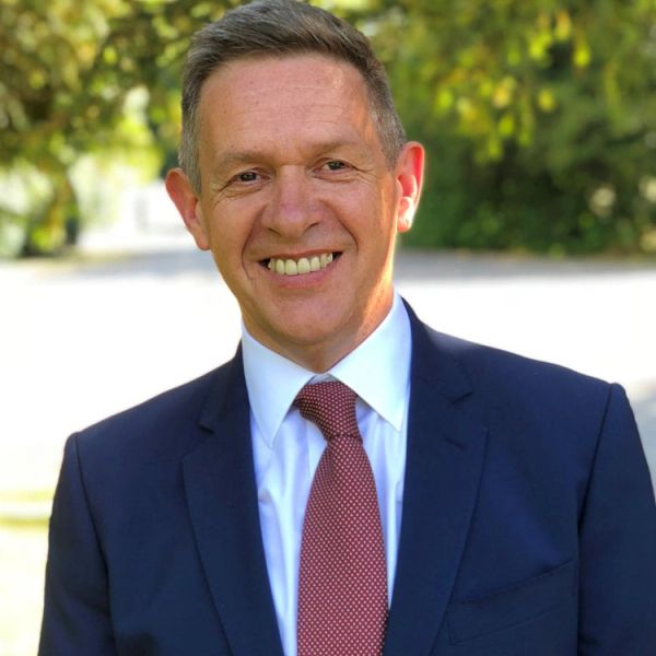 Man in suit smiling outdoors.