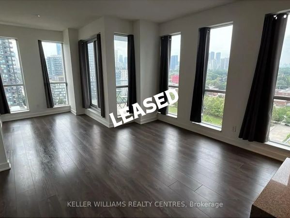 Spacious empty room with large windows and dark curtains.
