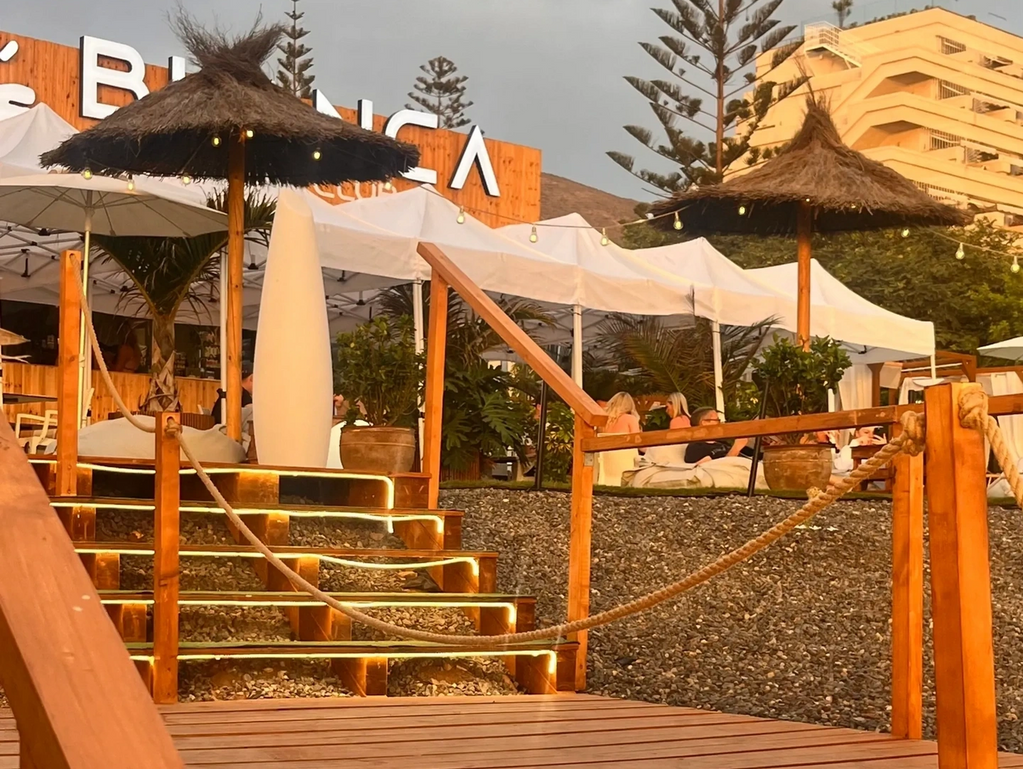 Cozy beachside lounge with thatched umbrellas and warm lighting at sunset.