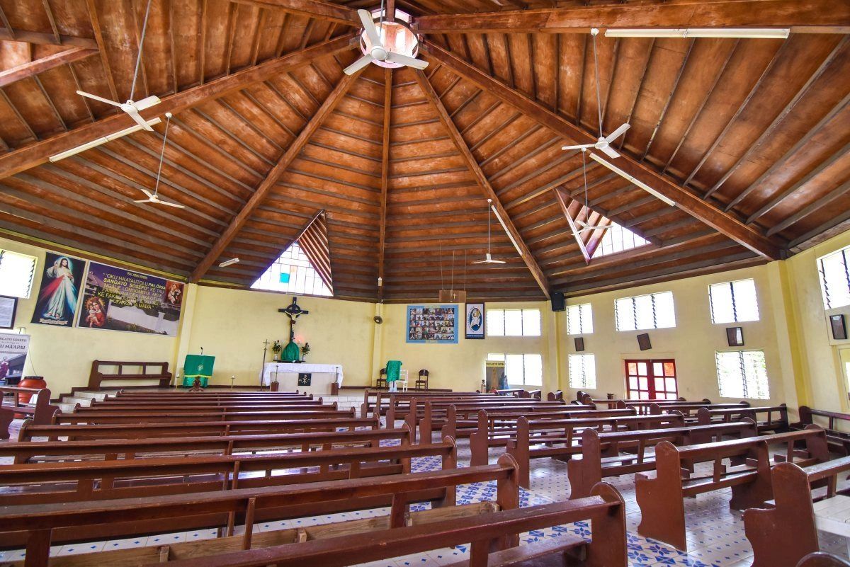 Interior of a spacious church with wooden ceiling and pews.
