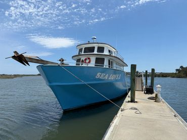 Blue boat named Sea Lover docked at a pier on a sunny day.