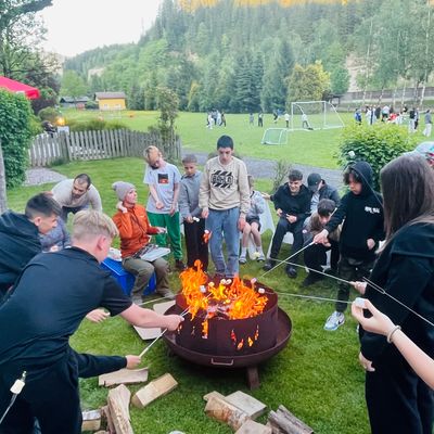 Gruppe junger Menschen röstet Marshmallows am Lagerfeuer.
