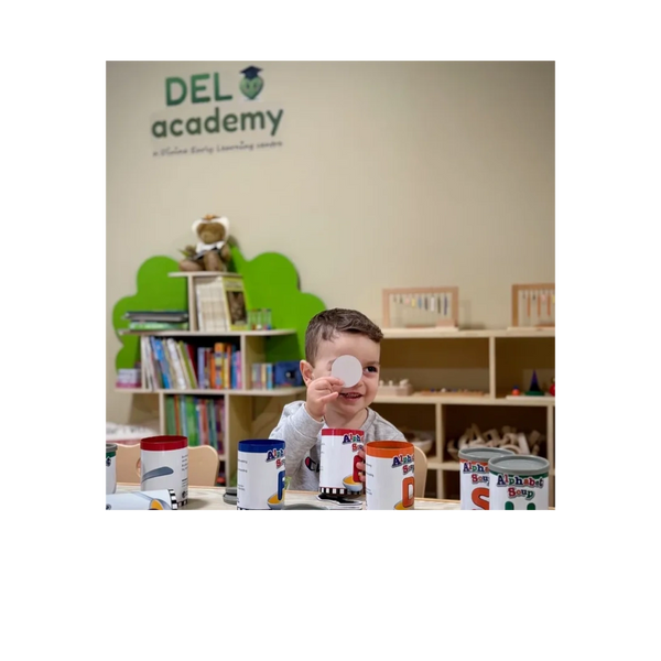 A smiling child playing with educational cans in a learning center.