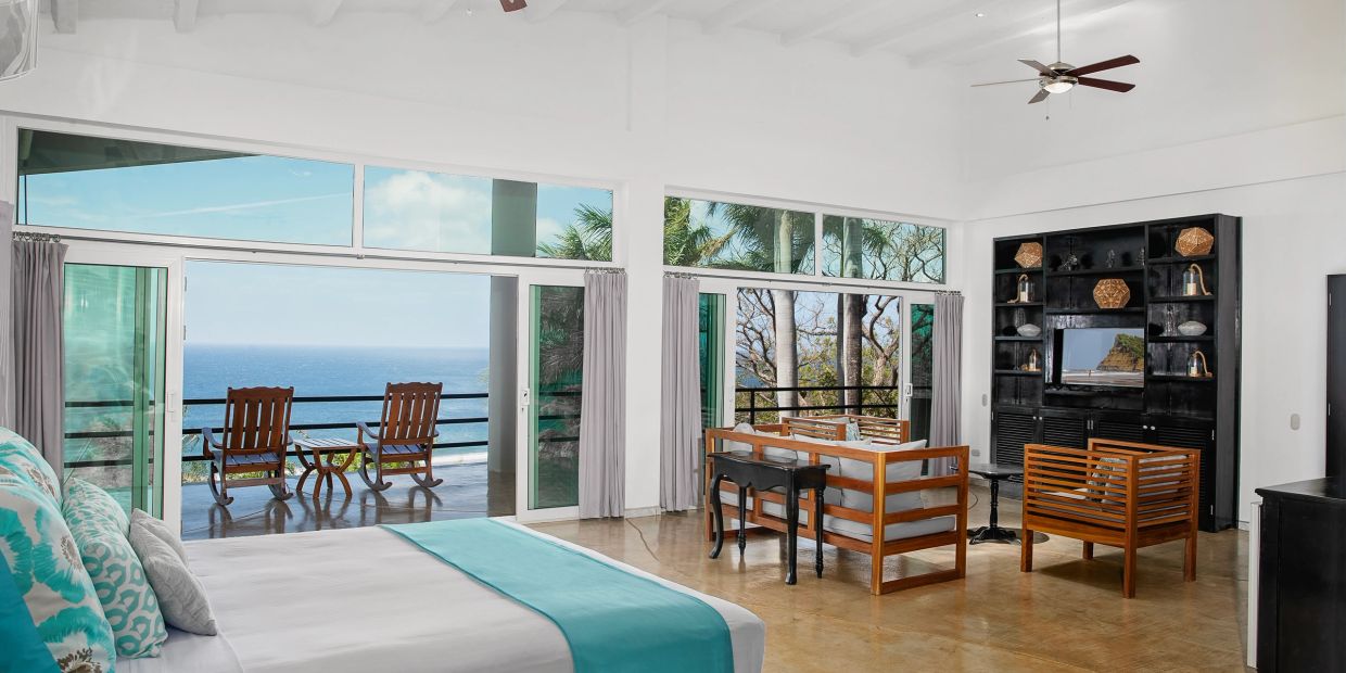 Spacious beachside room with balcony seating and ocean view.