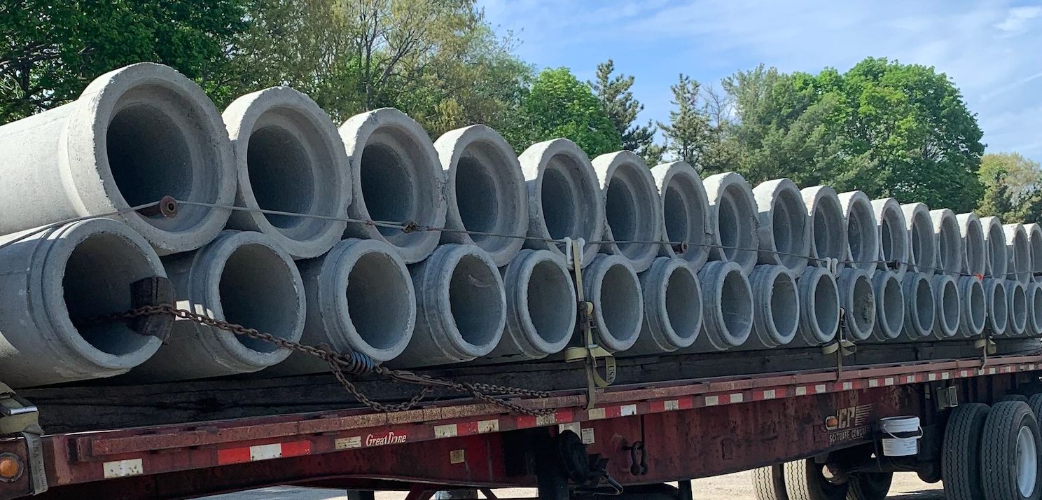 Concrete pipes stacked on a flatbed trailer ready for transport.