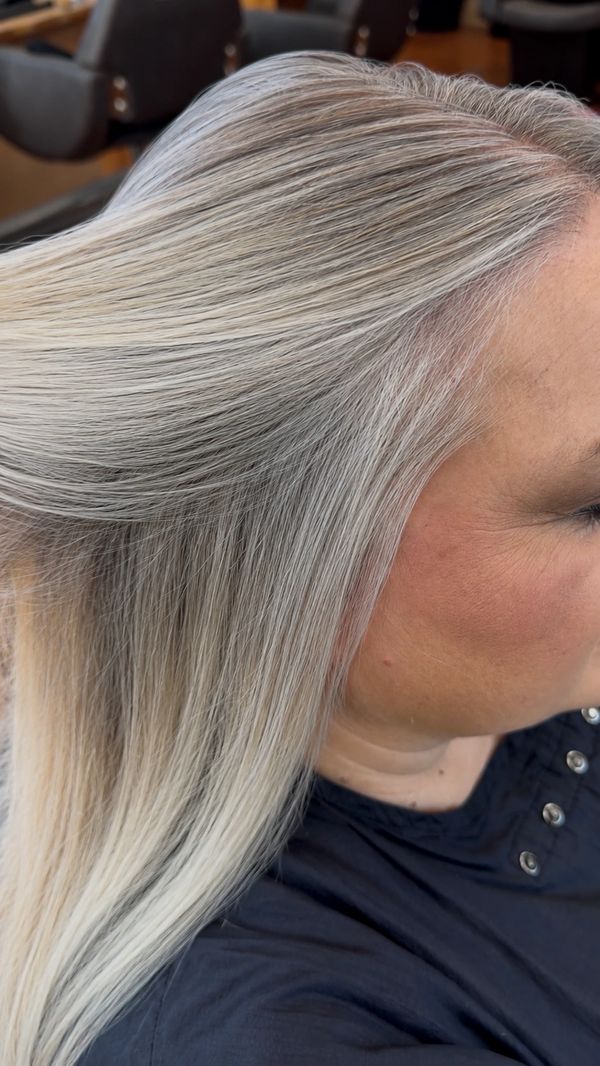 Side view of a person with smooth, silver-gray hair in a salon.