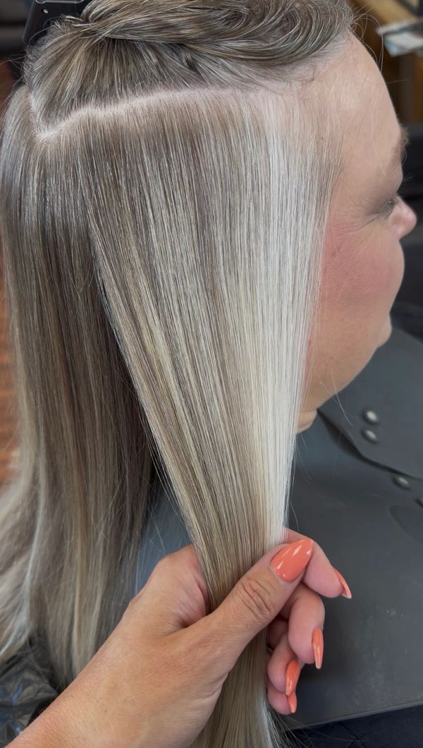 Close-up of a hand holding smooth, freshly colored blonde hair.