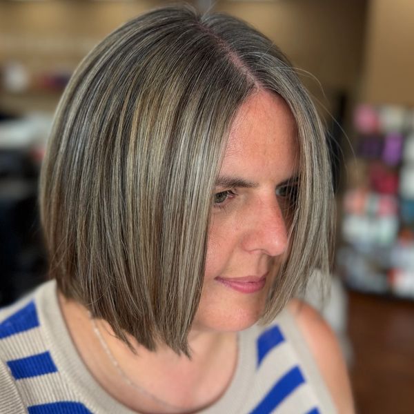 Woman with a sleek bob haircut featuring gray and blonde highlights.