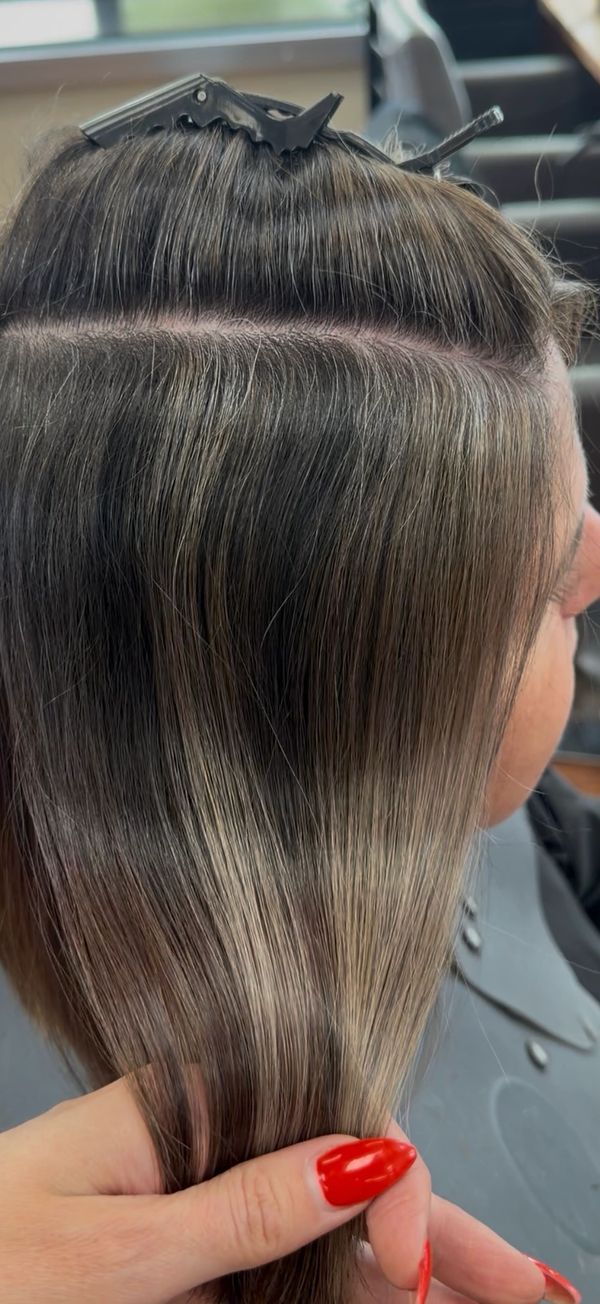 Close-up of smooth, straight hair section being held with red-painted nails.
