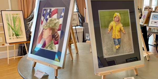 Paintings displayed on easels in an art exhibit room.