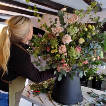 Wedding florist creating a large flower arrangement to be placed in an urn at the wedding