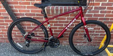 A sleek red Trek bicycle parked against a brick wall.
