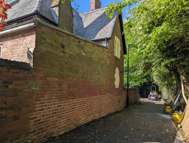 Path alongside a brick building with greenery.