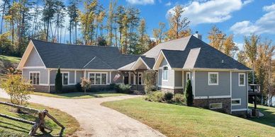 Spacious modern house with a large driveway and surrounded by autumn trees.