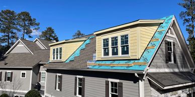 House undergoing roof renovation with new dormer windows.