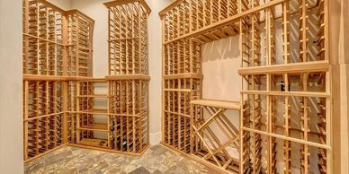 Empty wooden wine racks in a spacious cellar with tiled flooring.