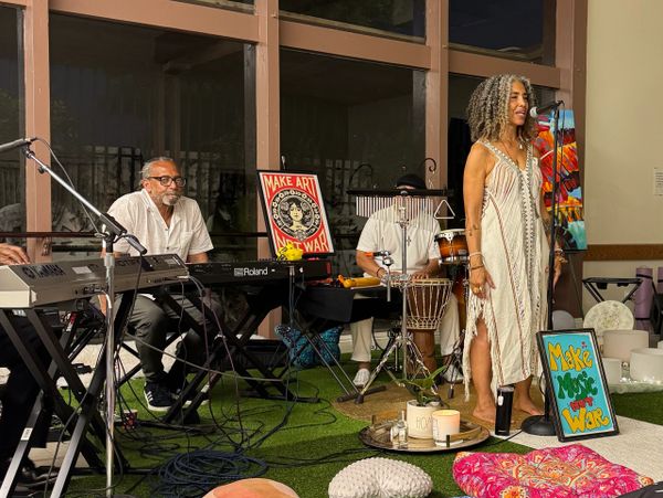 A soulful live music performance with vibrant signs promoting art and music for peace.