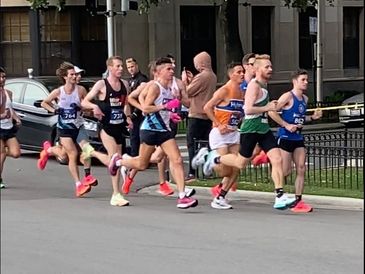 Group of men running in a race on city street.