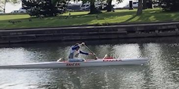 Person rowing a kayak on a calm river.