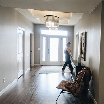 Woman walking through hallway with pretty light and glass door.