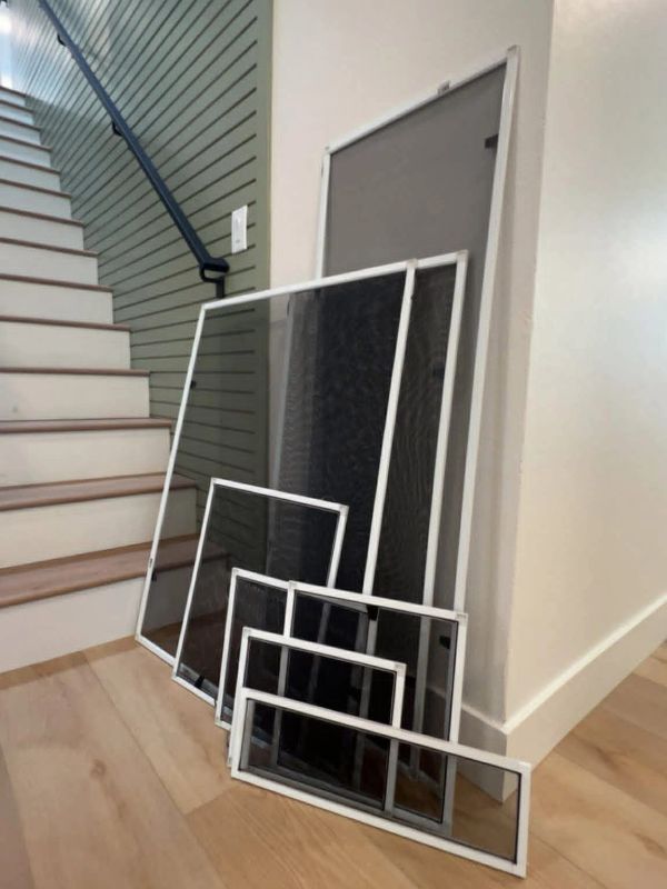 Various window screens leaning against a wall next to stairs.