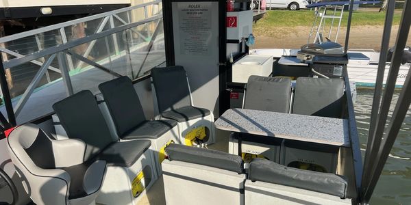 Seating area on a boat with black and gray cushioned chairs.