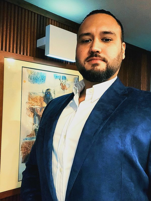 Man in a blue blazer and white shirt posing indoors.