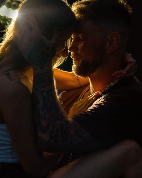 A couple shares an intimate moment in warm, soft light.