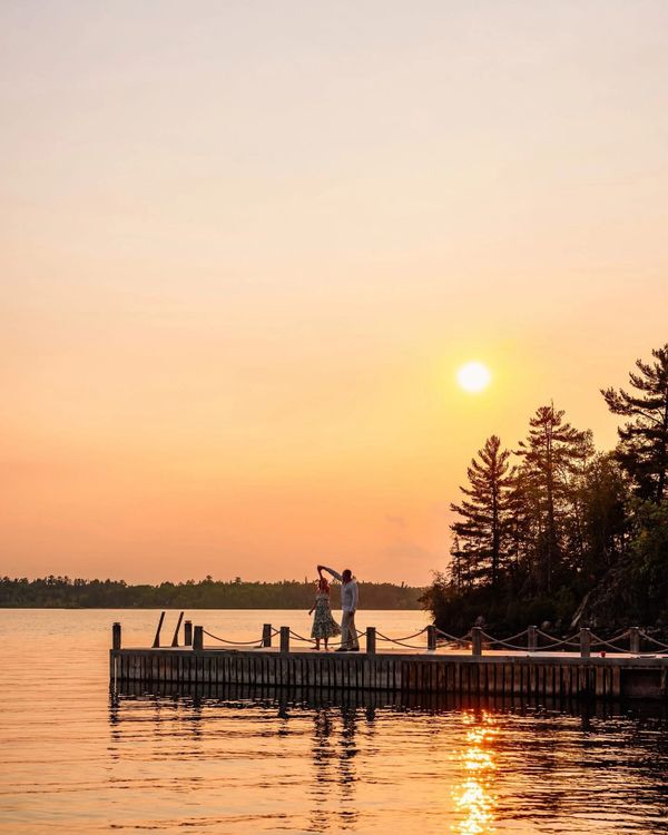 Couple dancing on a dock at sunset by the lake.
