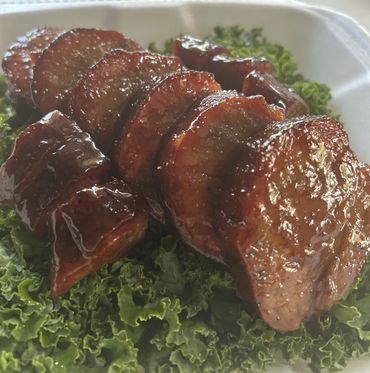 Glazed slices of barbecued pork served on fresh kale.