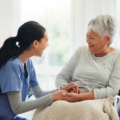 Happy woman, doctor and holding hands with senior patient in wheelchair.