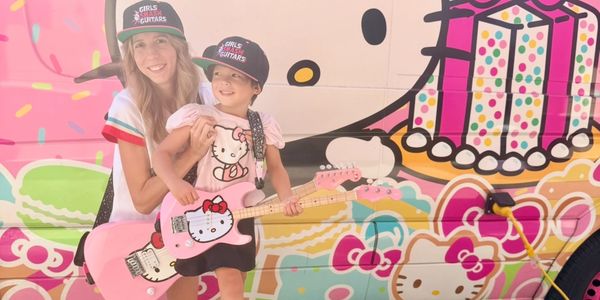 Woman and child with pink Hello Kitty guitars and matching hats.