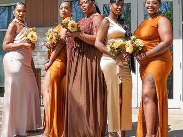 Five women in elegant dresses posing with bouquets.