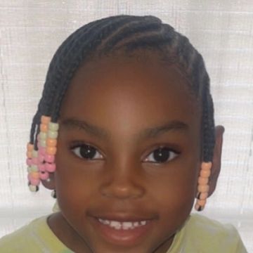 Smiling girl with braided hair and colorful beads.